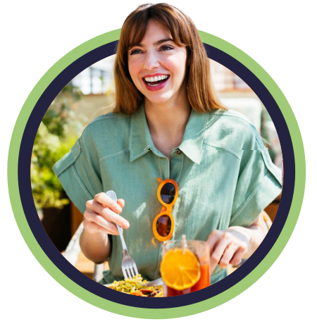 Woman in linen shirt smiling and eating breakfast on sunny patio