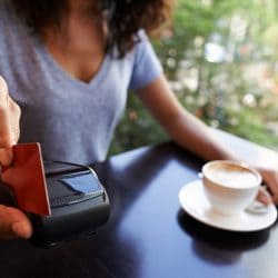 A woman in a café swipes her credit card in a portable card reader.