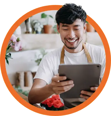 smiling man wearing apron uses mobile tablet