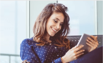 Woman smiling while looking at tablet.