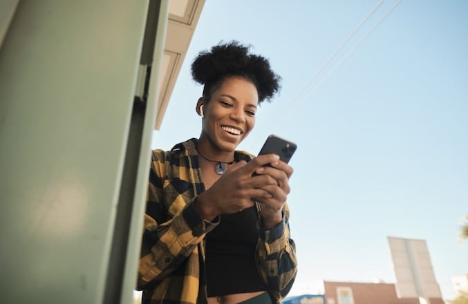 Young woman smiles after using her mobile app to deposit a check.