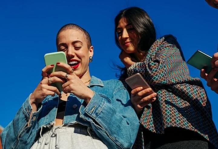 Two young women looking at their mobile devices.