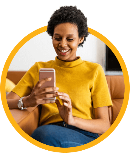 Woman with yellow shirt smiling while using her mobile device.