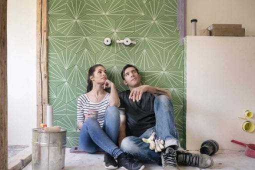 Couple renovating a new house, sitting on ground planning their bathroom