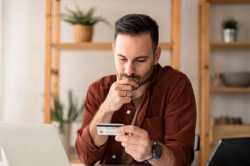 A man looks at the information on the front of his credit card.