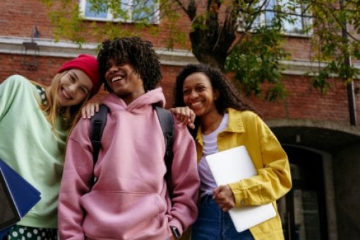 Three young students hang out on their college campus.