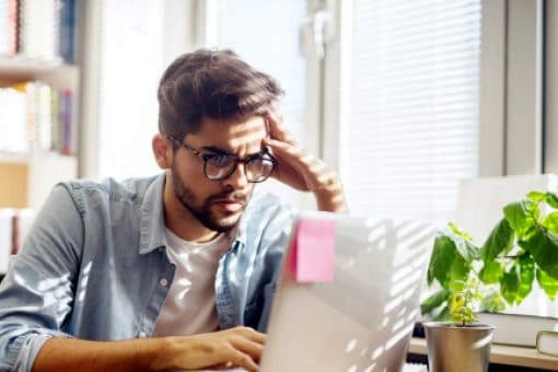 A young man searches the internet on his laptop for answers about credit card myths.