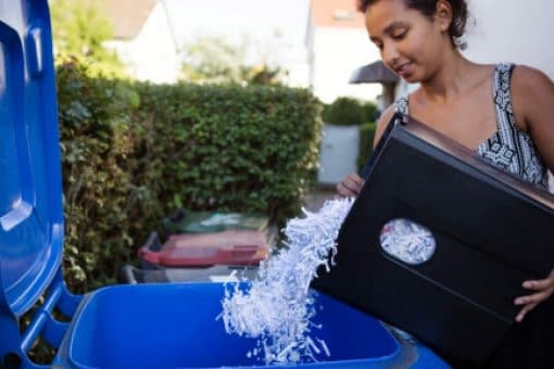 A young woman adds shredded documents to her recycling bin.