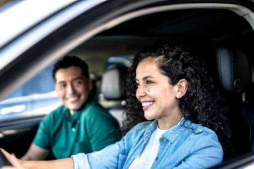 Mid adult woman driving a car with her husband at city