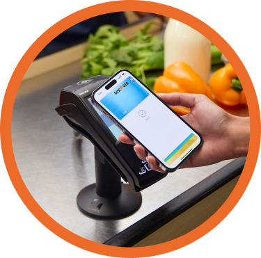 A person uses their mobile  wallet to pay with their instant  credit card from Discover by  tapping their phone at a grocery  store contactless payment  terminal.