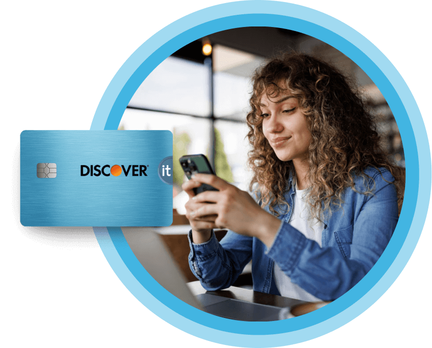 Smiling woman using a smartphone in a cafe, next to a Discover It credit card.