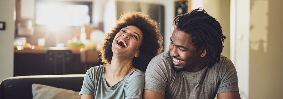 Couple sitting in their Texas living room and laughing together