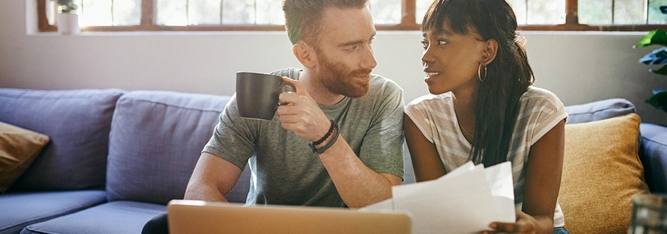 Husband and wife sitting in the living room, discussing the possibility of refinancing to a 15-year mortgage.