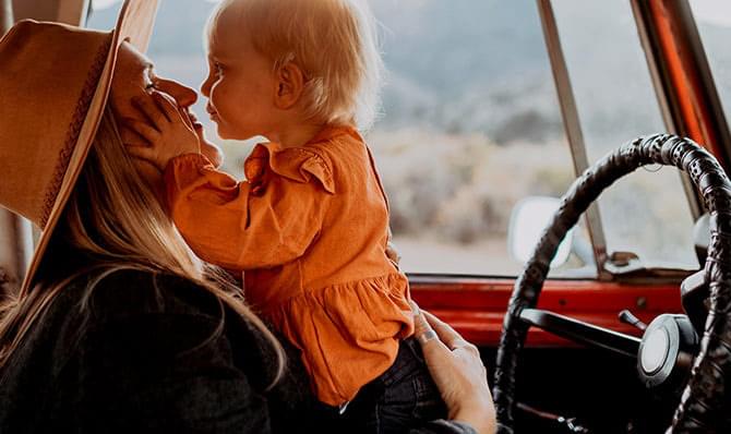 A woman kisses her child in the front seat of a truck.