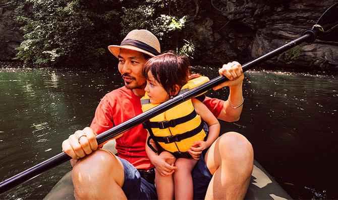 A man and a child in a canoe on a river.